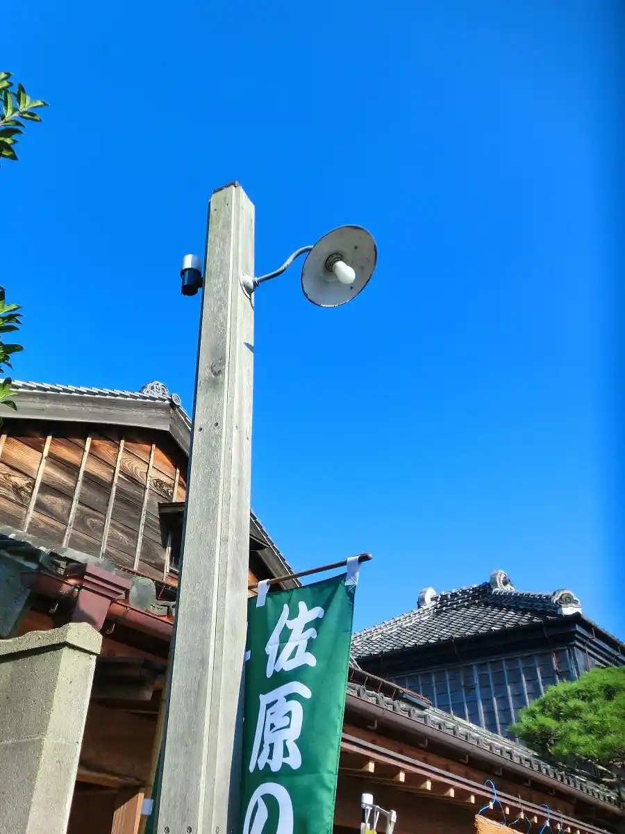 A low-angle photo shows a wooden pole with a vintage-style street lamp and a small security camera mounted on it, against a…