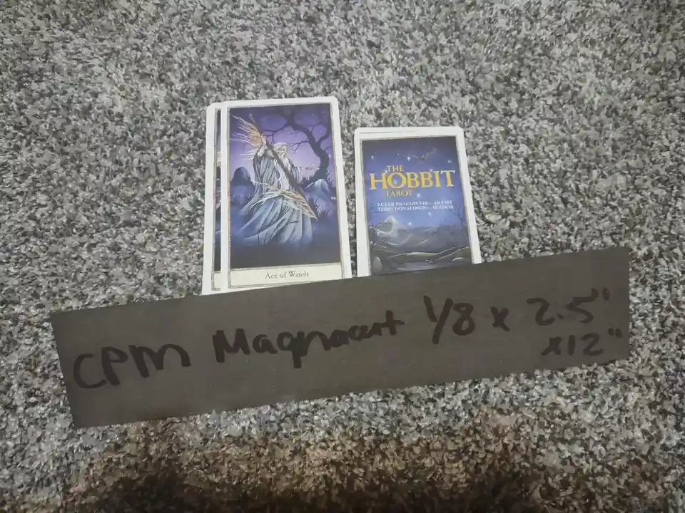 Two tarot card decks are laid out on a speckled gray carpet. The left deck shows the 'Ace of Wands' card featuring a…