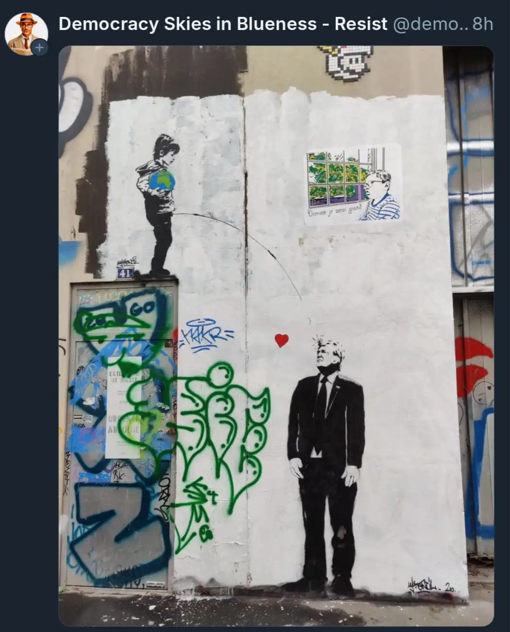 A street art mural shows a boy holding a globe on the left and a man in a suit on the right, with a red heart between them…
