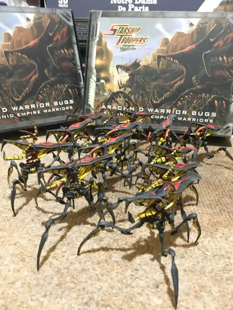 A collection of painted black, yellow, and red insectoid miniatures, resembling the Arachnid Warrior Bugs from the Starship…