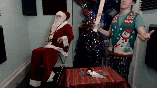A person in a Christmas sweater swings a bat at a ball while sitting in a Santa costume, then turns around and hits the…