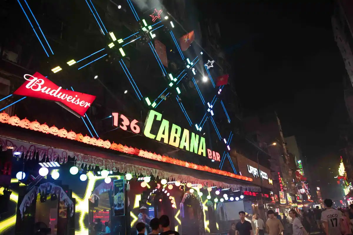 A nighttime photo of a brightly lit bar named '136 CABANA BAR' decorated with Halloween-themed jack-o'-lanterns and neon…