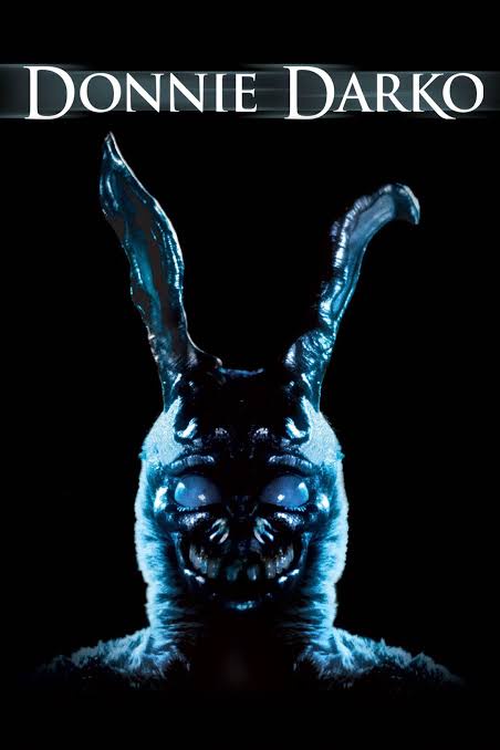 A dark movie poster for 'Donnie Darko' features a menacing, blue-tinted bunny costume with glowing eyes and sharp teeth, set…