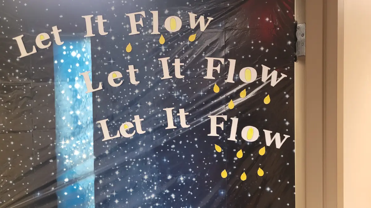 A poster on a door features the phrase 'Let It Flow' repeated three times in white text against a dark, starry background…