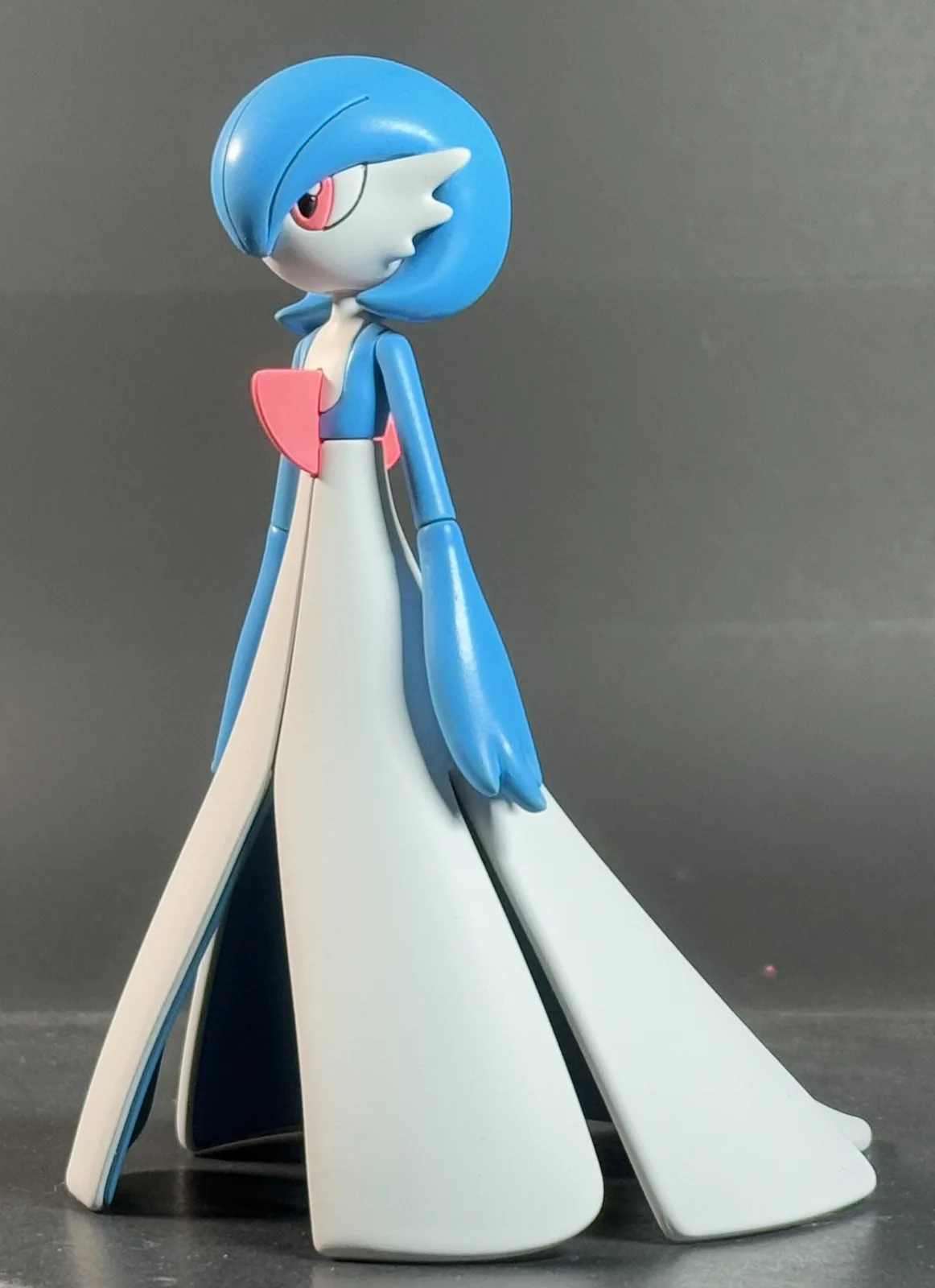 A plastic figurine of the Pokémon character Diancie, shown in profile against a plain gray background, is overlaid with the…