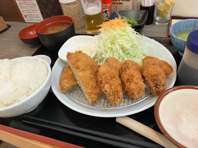 a close-up photo of a Japanese meal featuring a plate of golden-brown, breaded fried chicken katsu on a wire rack…