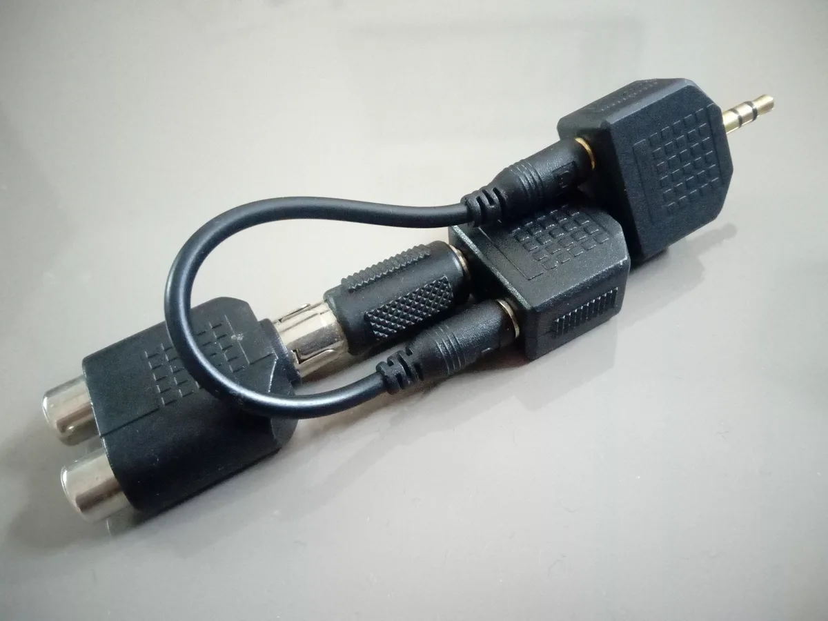 A black cable adapter with multiple connectors, including a 3.5mm jack, RCA plugs, and a BNC connector, is shown tangled on…