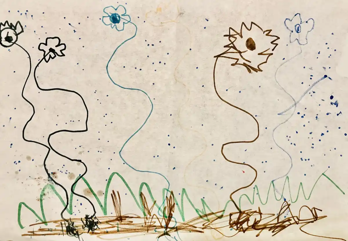 A child's crayon drawing on textured paper shows abstract, wavy figures with flower-like heads and scribbled roots. The…