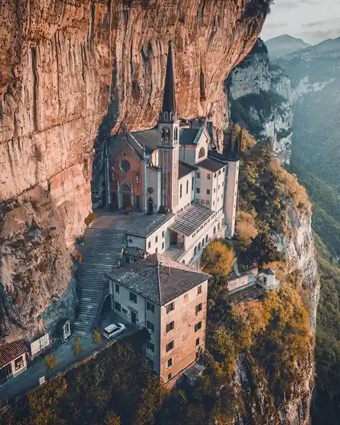 an aerial view of a stunning church built directly into a massive cliffside, with a steep staircase leading up to its…
