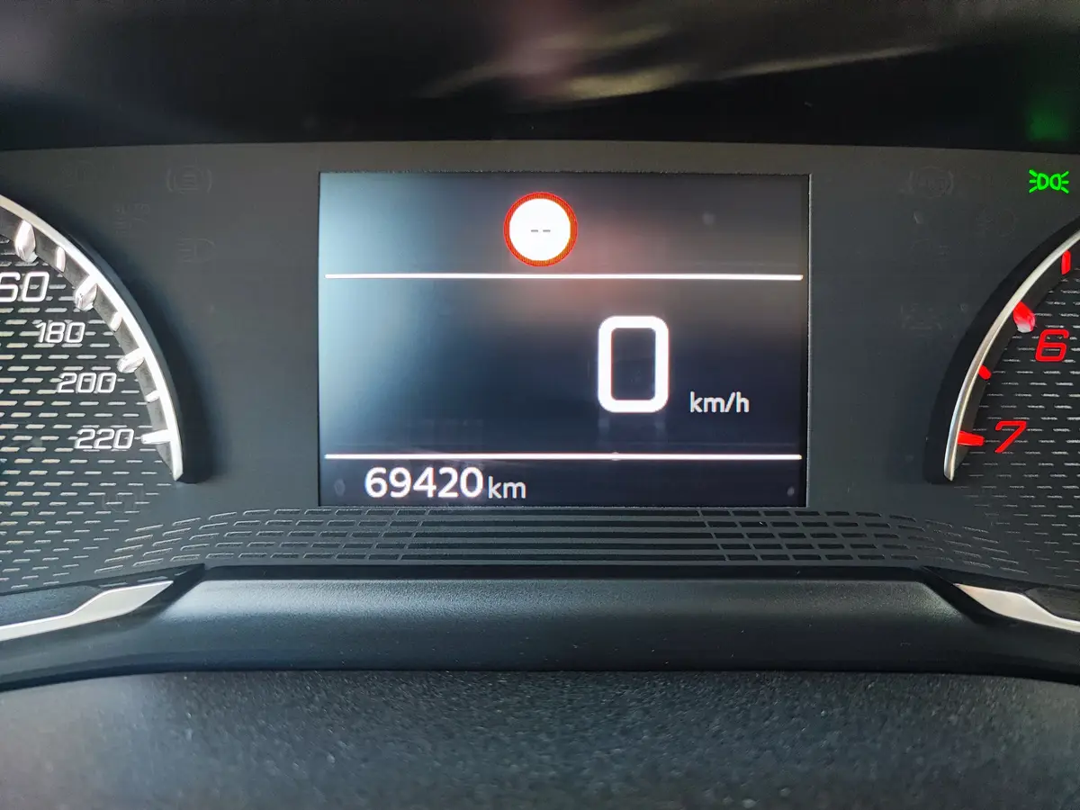 A car's digital dashboard shows a speed of 0 km/h and an odometer reading of 69420 km, with a red warning light illuminated…