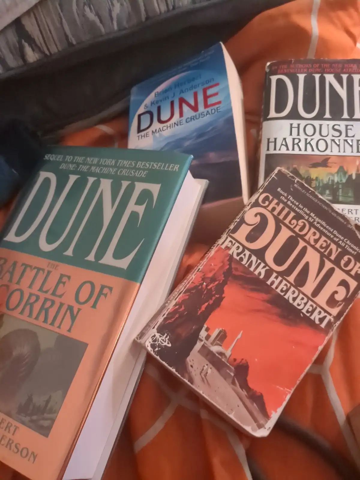 Four Dune series books are stacked on an orange and white patterned blanket: 'Dune: The Machine Crusade' by Brian Herbert &…