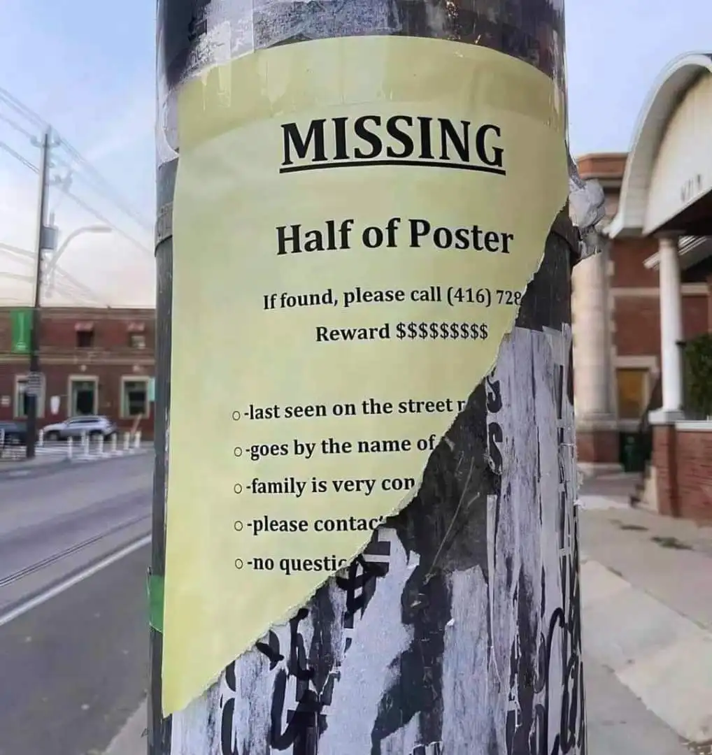 A torn yellow missing person poster is taped to a utility pole, with the top half intact and the bottom half ripped away…