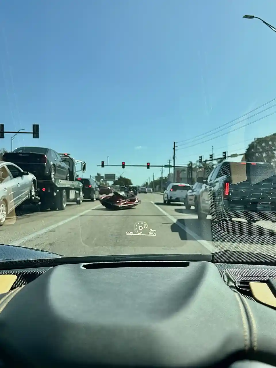 A dashcam view from inside a car shows a red motorcycle lying on its side in the middle of a traffic jam at a red light…