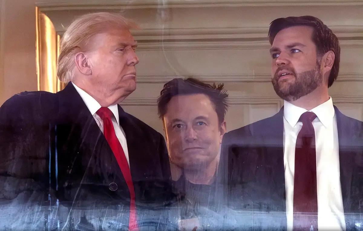 The image shows three men in suits: Donald Trump on the left with a stern expression, Elon Musk in the center looking…