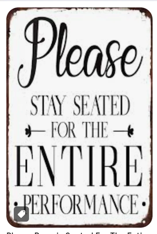 A vintage-style white sign with black text and a distressed border reads 'Please STAY SEATED FOR THE ENTIRE PERFORMANCE' in…