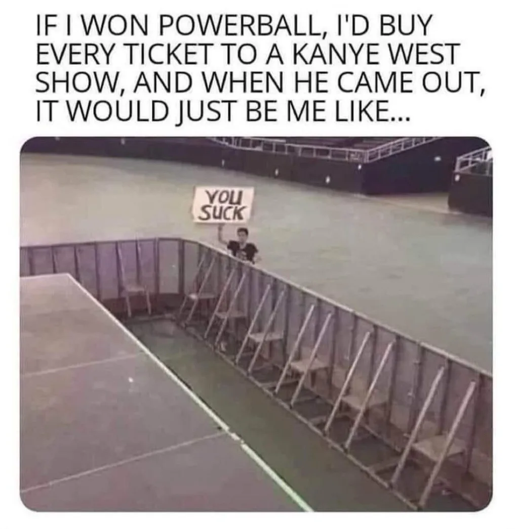 A person stands behind a barrier at a concert venue holding a handmade sign that reads 'YOU SUCK'. The top text explains the…
