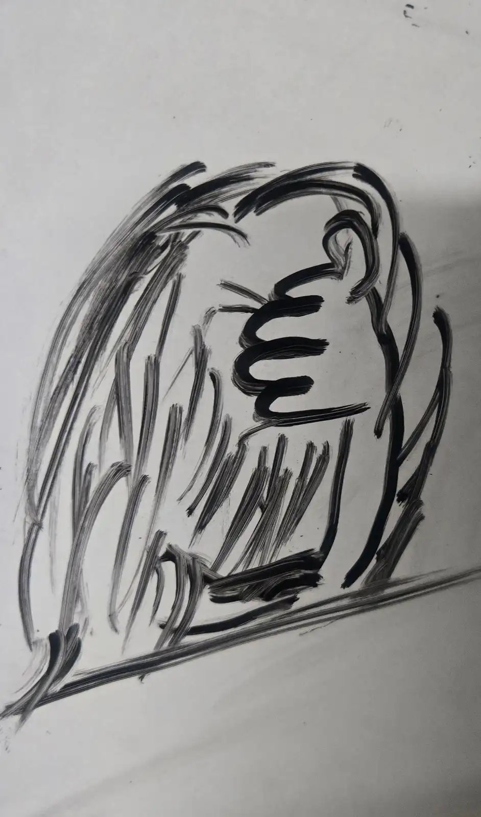 A crude black-and-white sketch on white paper depicts a crudely drawn face with wild, scribbled hair, a squiggly mouth, and…