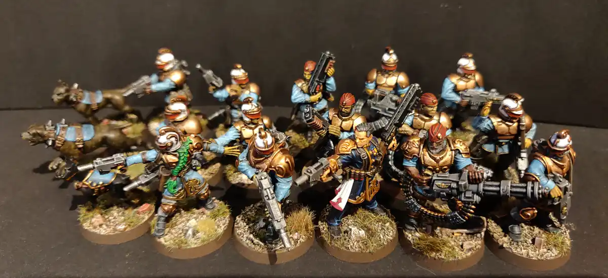 A collection of intricately painted miniature figurines, resembling futuristic or fantasy soldiers in blue and gold armor…