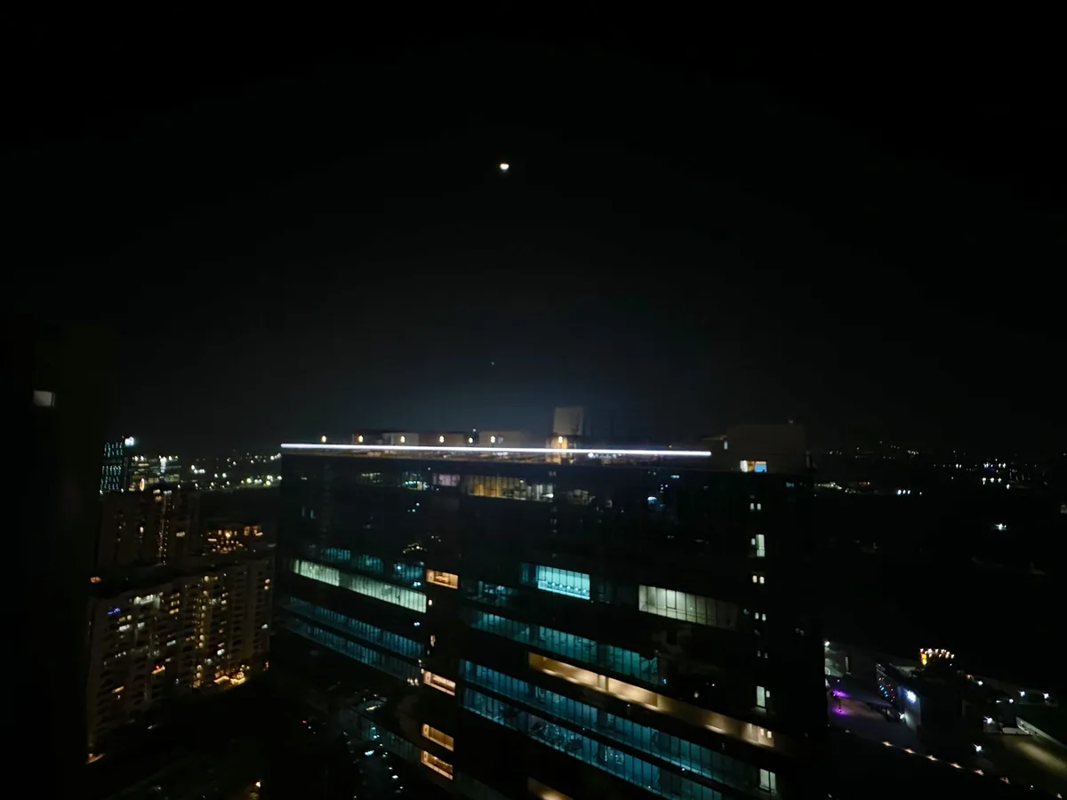 A nighttime cityscape photo showing a dark sky with a faint moon above a lit-up building, with the overlaid text 'i saw the…