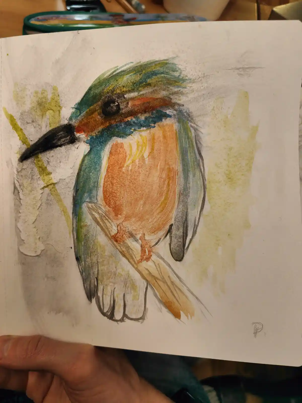 A hand holds a sketchbook page displaying a watercolor and pencil drawing of a colorful bird with blue, green, orange, and…