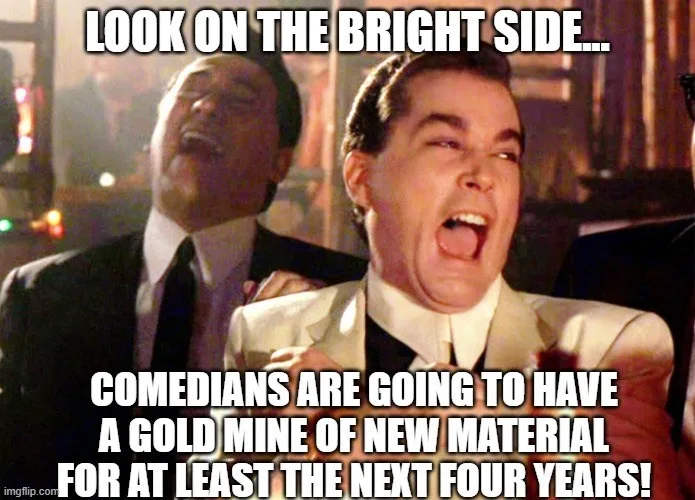 The image shows two men in suits, one in the foreground with his mouth wide open in an exaggerated expression of excitement…