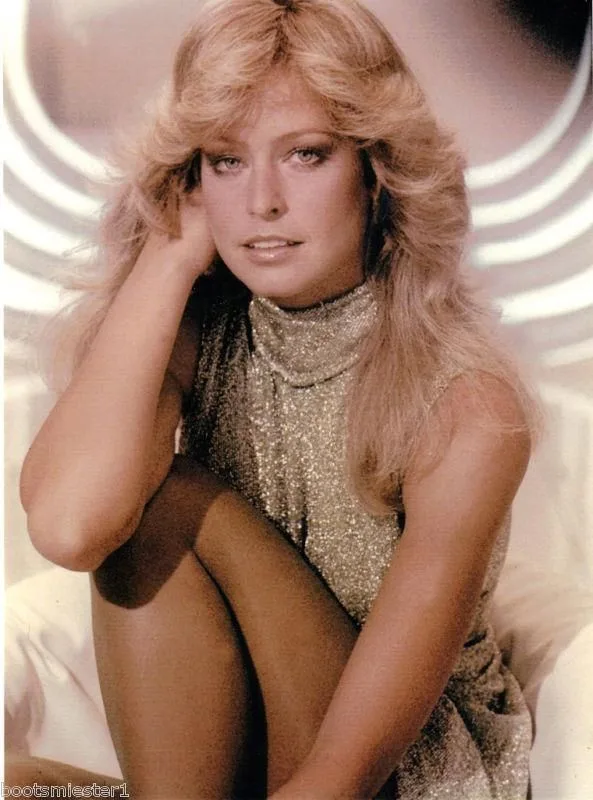 A woman with voluminous blonde hair sits in a sparkly gold top, hand resting on her head, looking concerned. The overlaid…