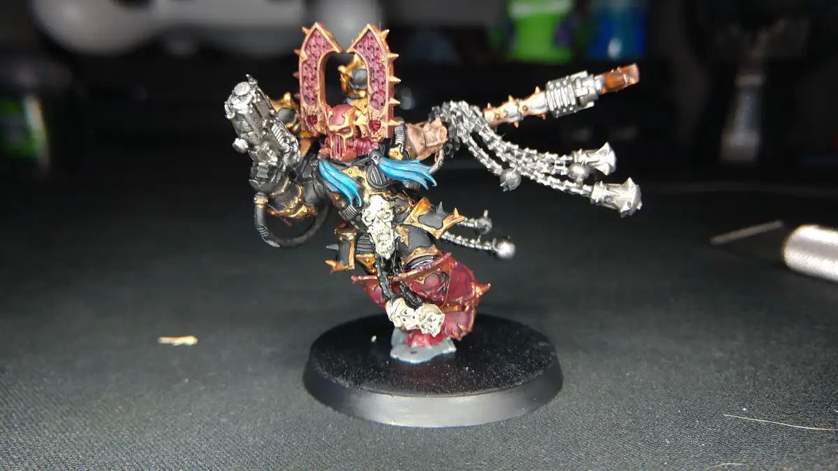 A heavily detailed, custom-painted miniature of a Warhammer 40,000 Chaos Space Marine stands on a black circular base…