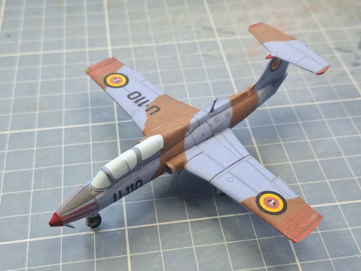 A paper airplane model with light blue and brown camouflage, featuring roundels and the text 'u-110' on its wings, rests on…