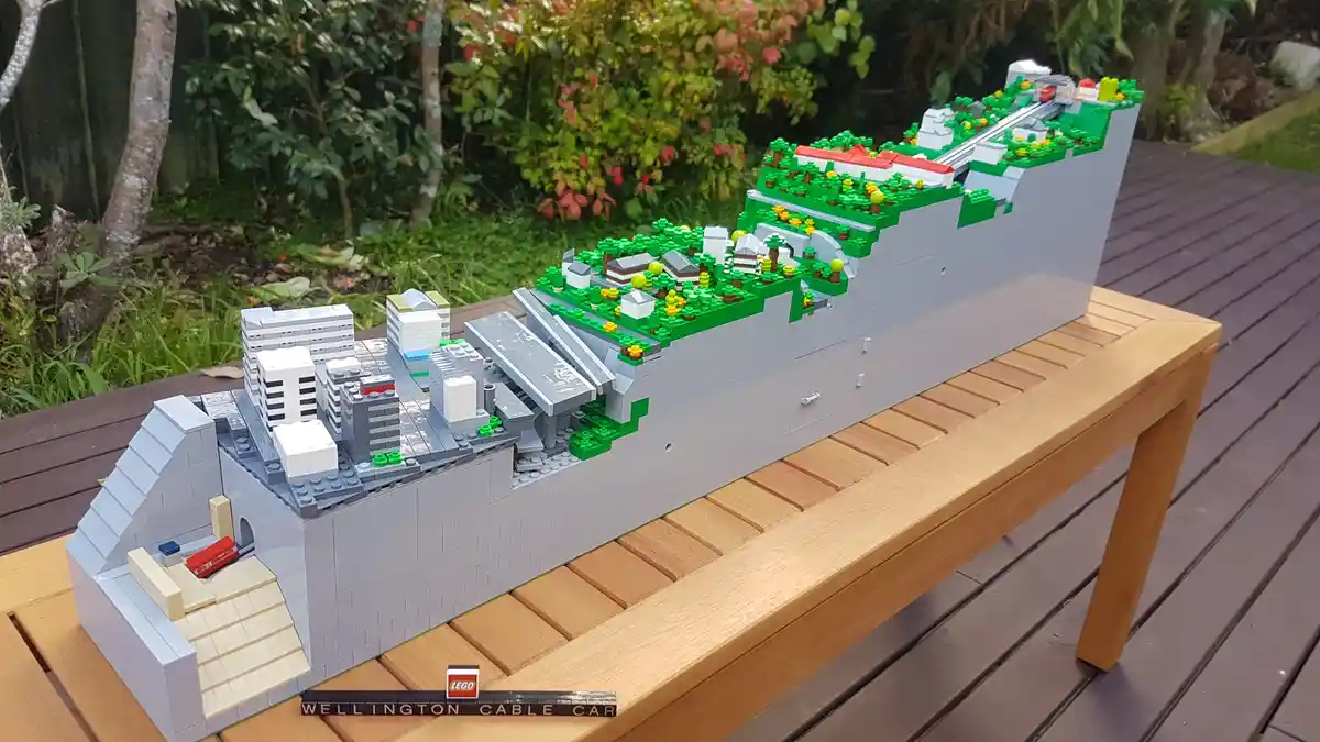A detailed LEGO model of the Wellington Cable Car system, featuring miniature buildings, greenery, and cable car tracks…