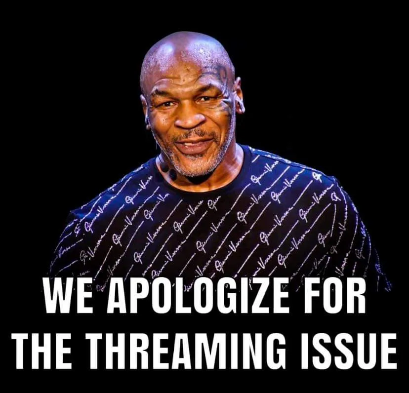 A photo of Mike Tyson smiling, wearing a black t-shirt with repeating 'Gucci' logos, against a black background. Large white…