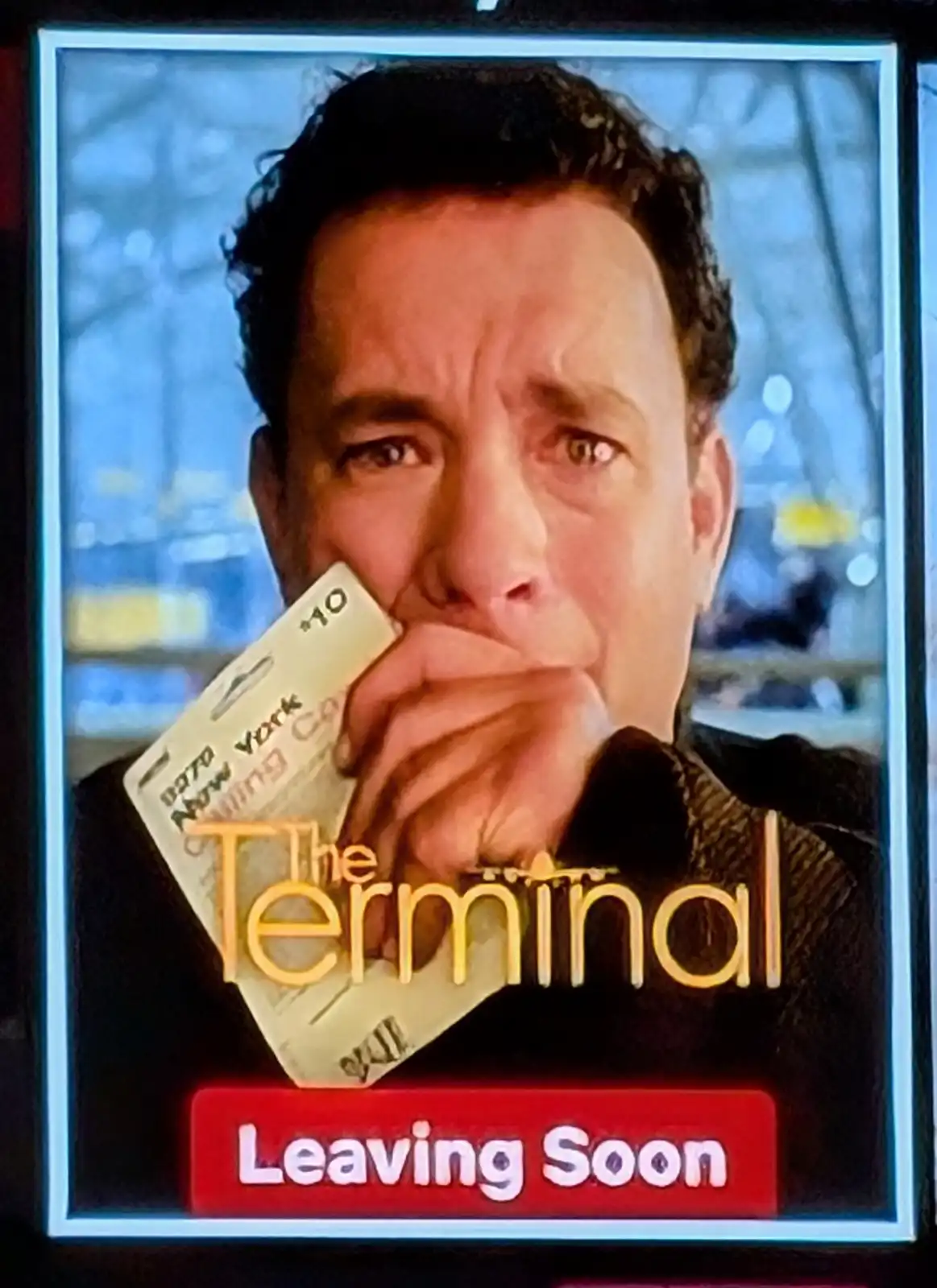 A close-up of Tom Hanks in the movie 'The Terminal' holding a boarding pass to New York, looking anxious as if about to…