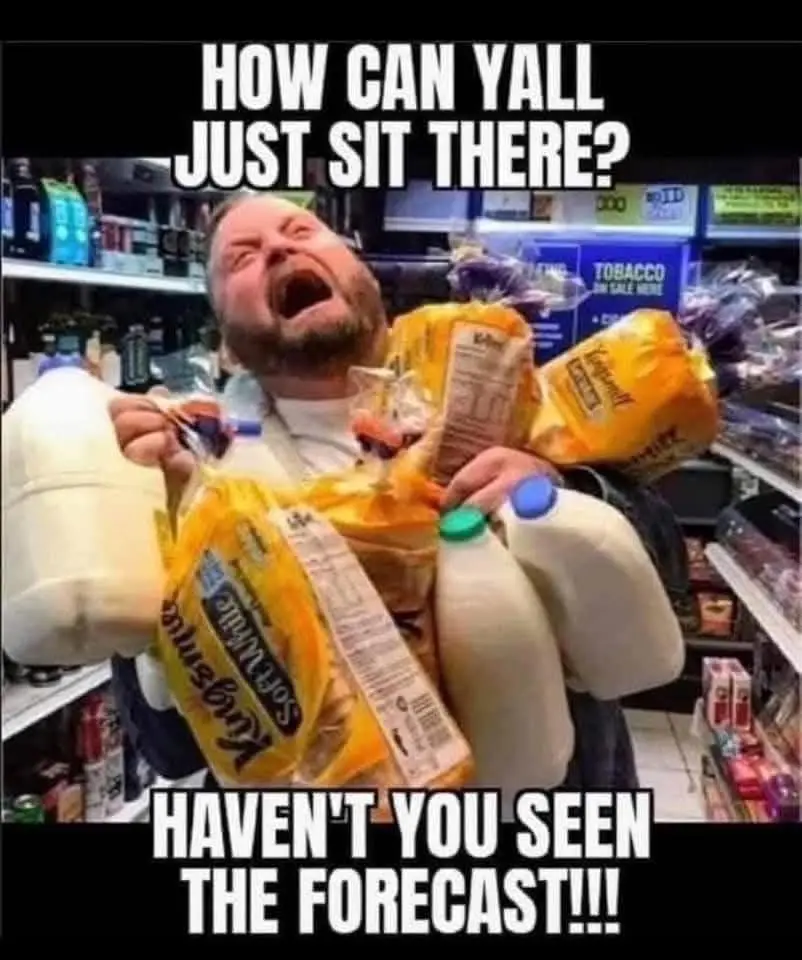 A man in a grocery store aisle is visibly overwhelmed, holding multiple bags of groceries including King's Hawaiian bread…