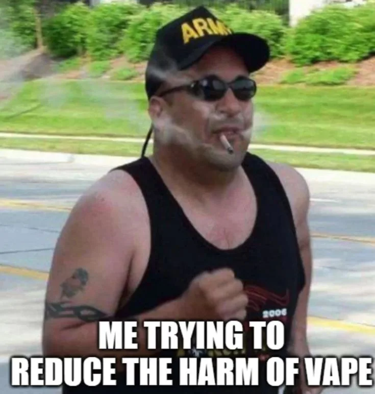 A man wearing a black 'ARMY' cap, sunglasses, and a black tank top is jogging outdoors with a cigarette in his mouth. He has…