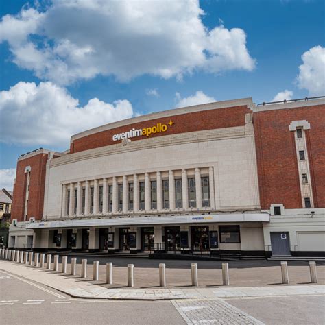 An exterior photo of the Eventim Apollo venue in London, showing its brick and stone facade under a partly cloudy blue sky…