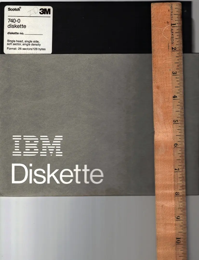 A vintage IBM diskette in its gray protective sleeve, labeled with a 3M Scotch 740-0 sticker indicating it's a…
