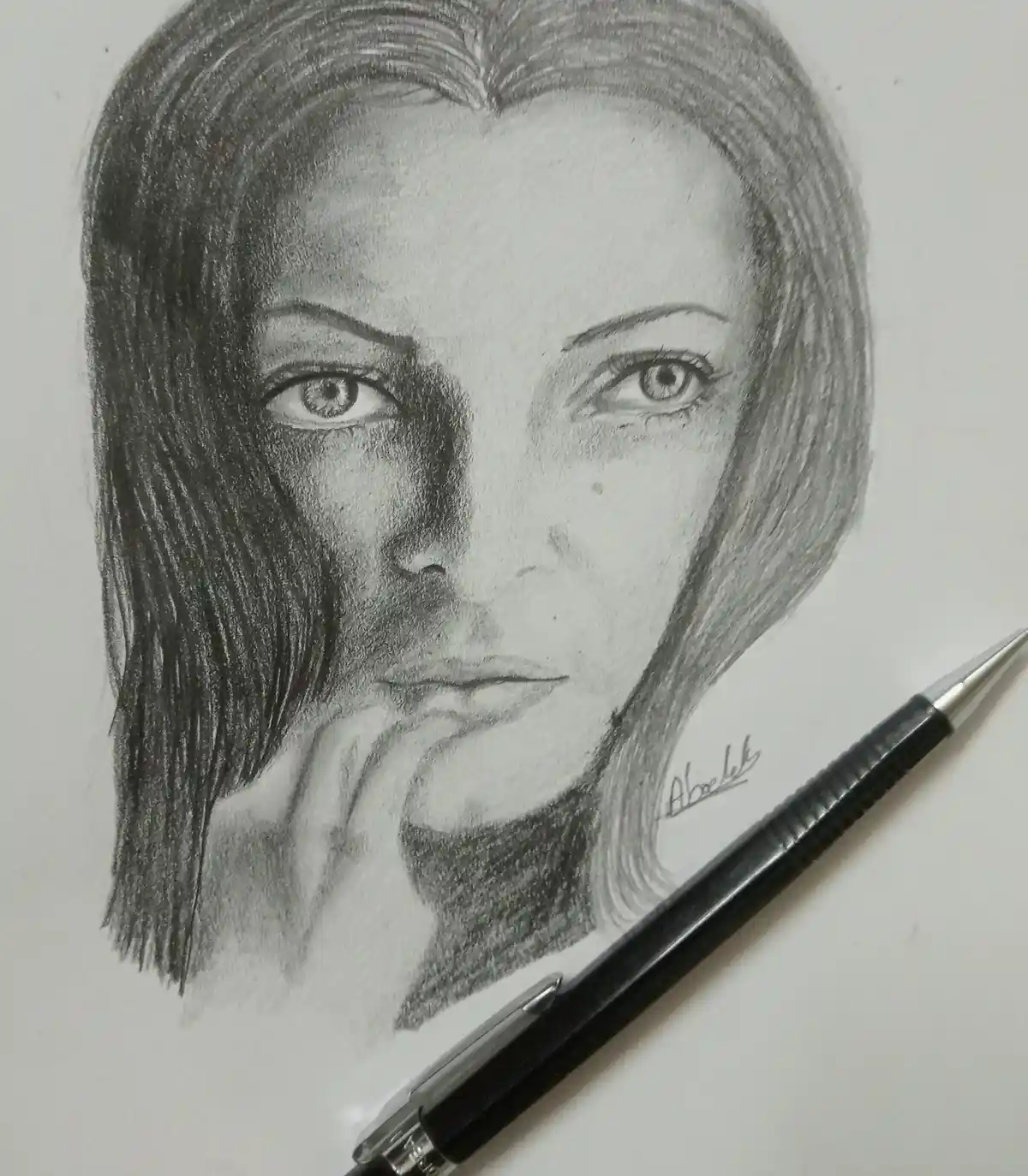 A detailed pencil sketch of a woman's face on white paper, with her left half heavily shaded and her right half lightly…