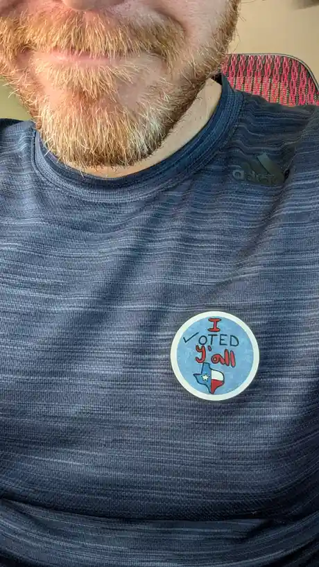 A close-up photo shows the lower face and chest of a person with a reddish beard wearing a dark blue Adidas t-shirt. On the…