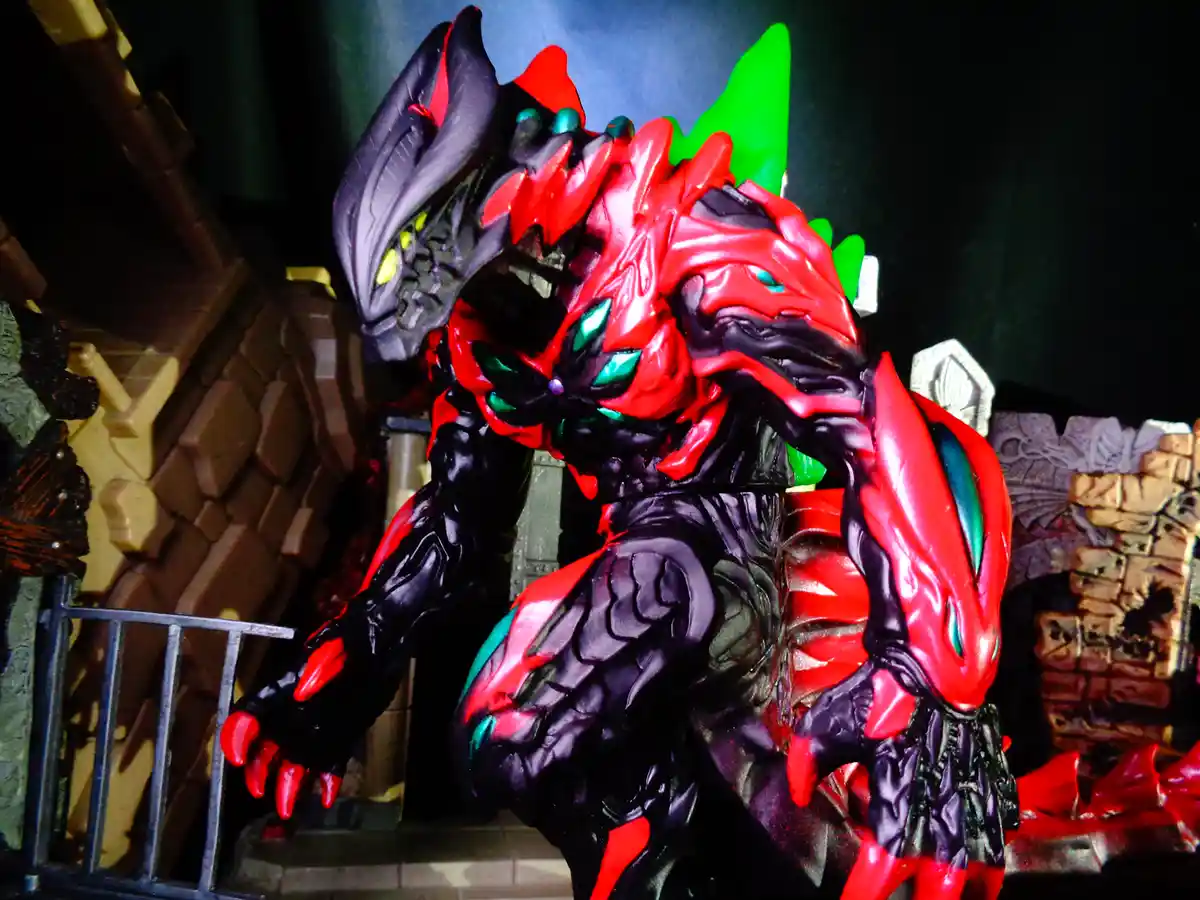 A menacing red and black monster figure with glowing green eyes and sharp claws stands in a dark, castle-like setting. The…