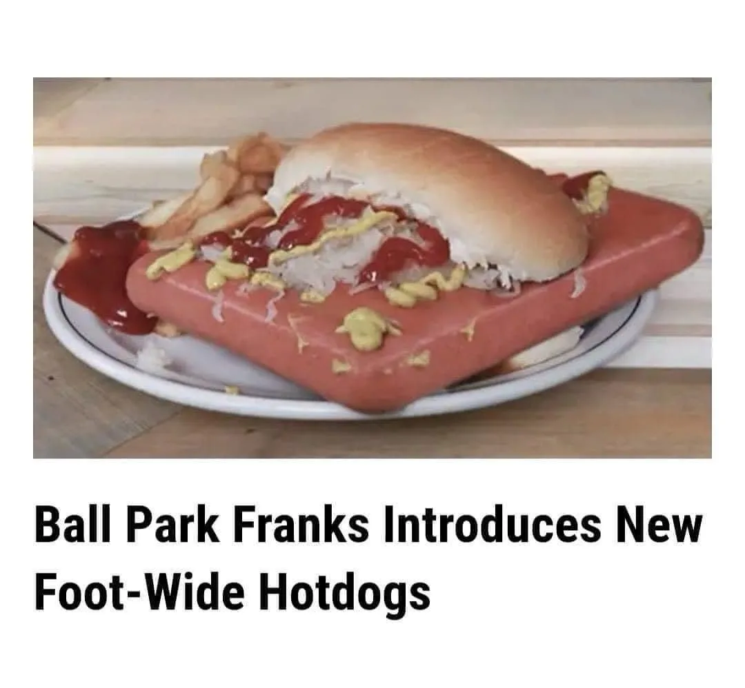 A close-up photo shows a giant, rectangular hot dog in a bun, topped with ketchup and mustard, sitting on a plate with…