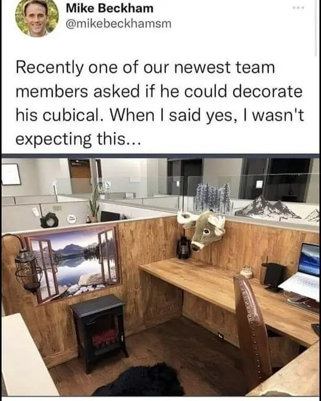A tweet from Mike Beckham shows a decorated office cubicle featuring a faux fireplace, a window mural of a lake, a deer head…