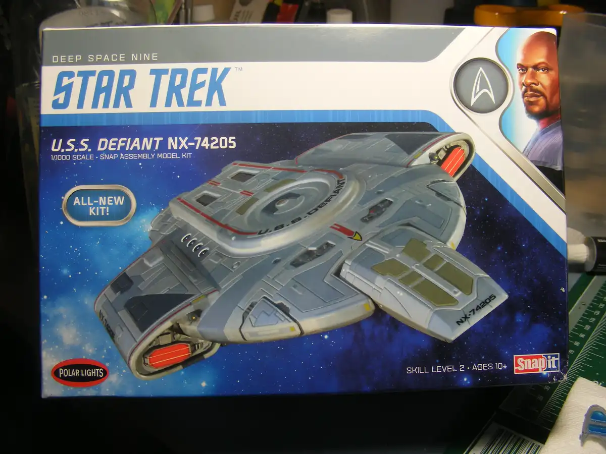 A box for a Star Trek U.S.S. Defiant NX-74205 snap assembly model kit, featuring an image of the spaceship and a portrait of…