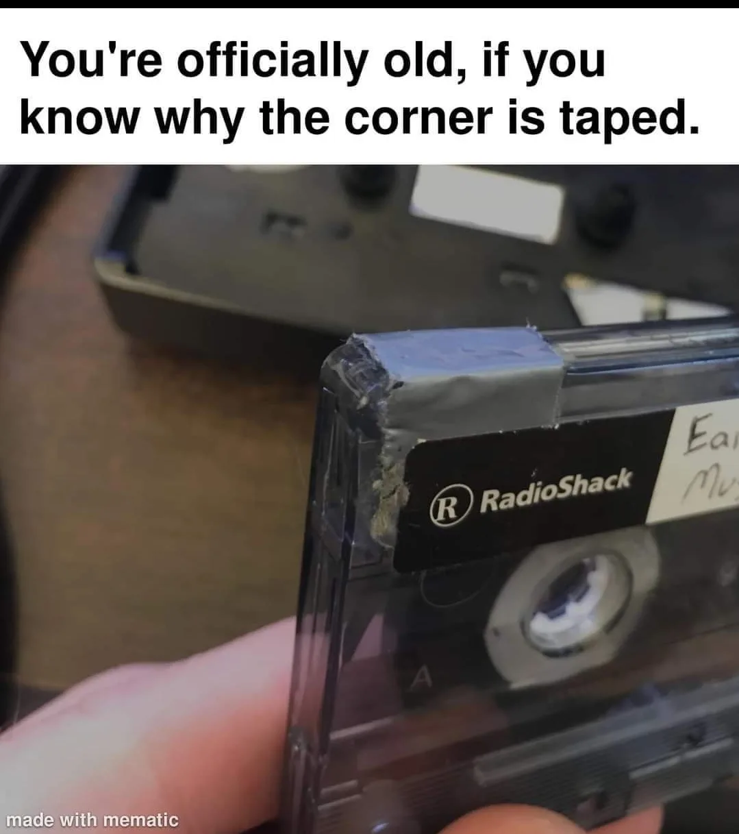 A close-up photo shows a hand holding a transparent RadioShack cassette tape with a piece of gray duct tape on its top…