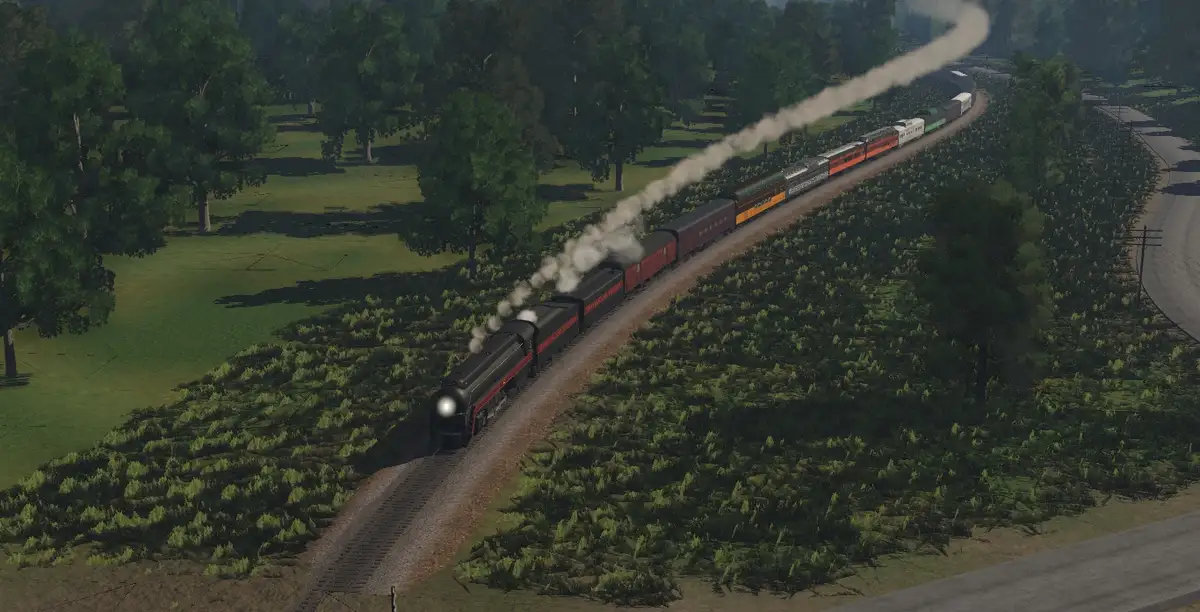 A long steam train with multiple colorful passenger cars travels along a curving track through a lush green forest and…