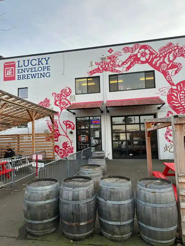 The exterior of Lucky Envelope Brewing features a white brick wall with large red Chinese zodiac animal murals, including a…