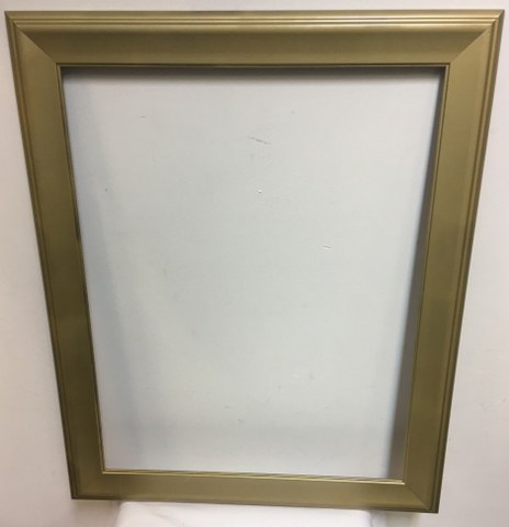 A plain gold-colored picture frame with a blank white interior, mounted on a white wall. The frame has a simple, slightly…