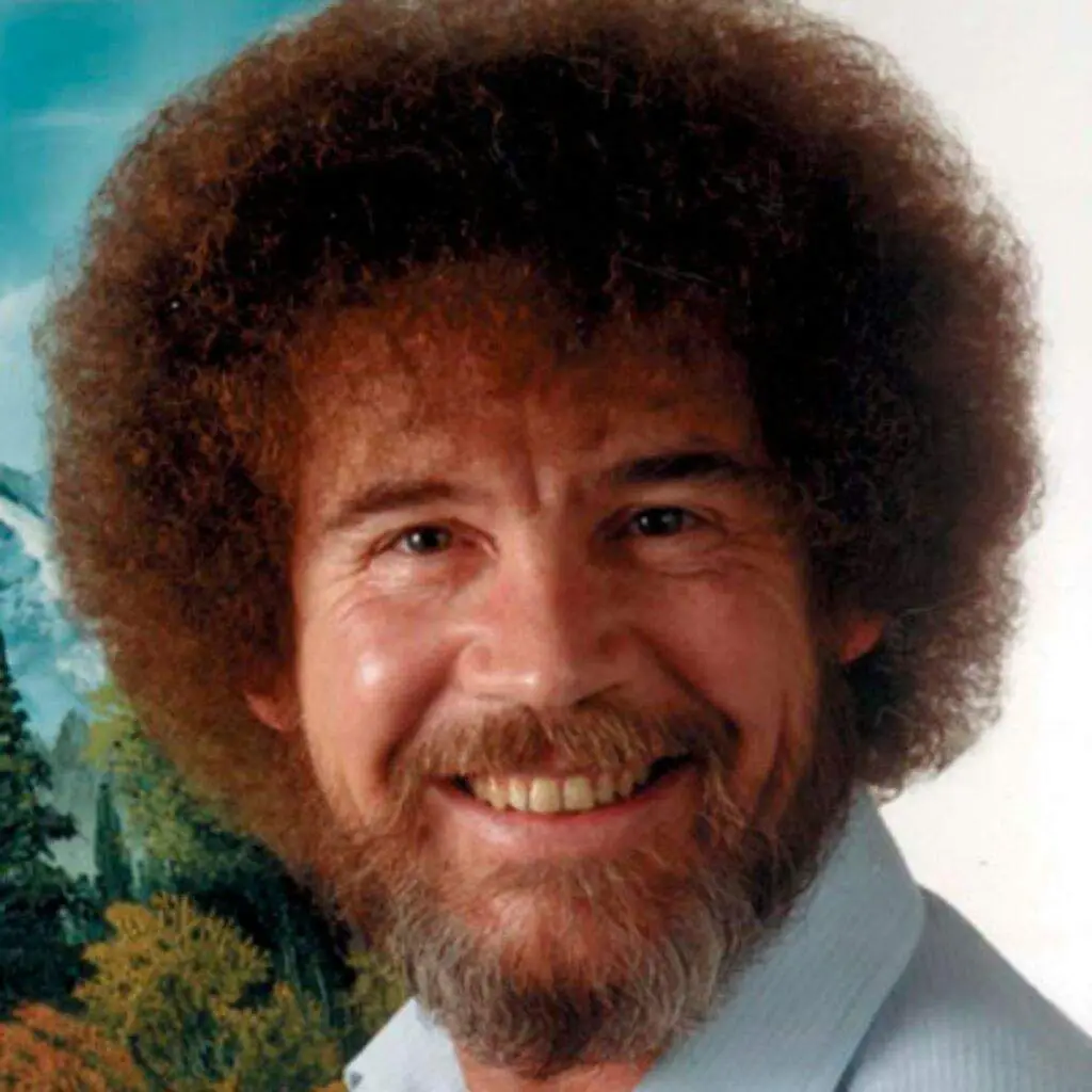 A close-up portrait of Bob Ross, the famous painter, smiling warmly with his signature curly brown hair and beard, wearing a…