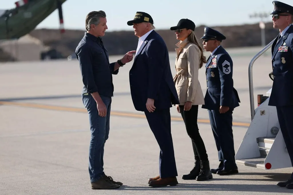 A photo shows former President Donald Trump, wearing a 'MAKE AMERICA GREAT AGAIN' cap, standing on an airfield and gesturing…