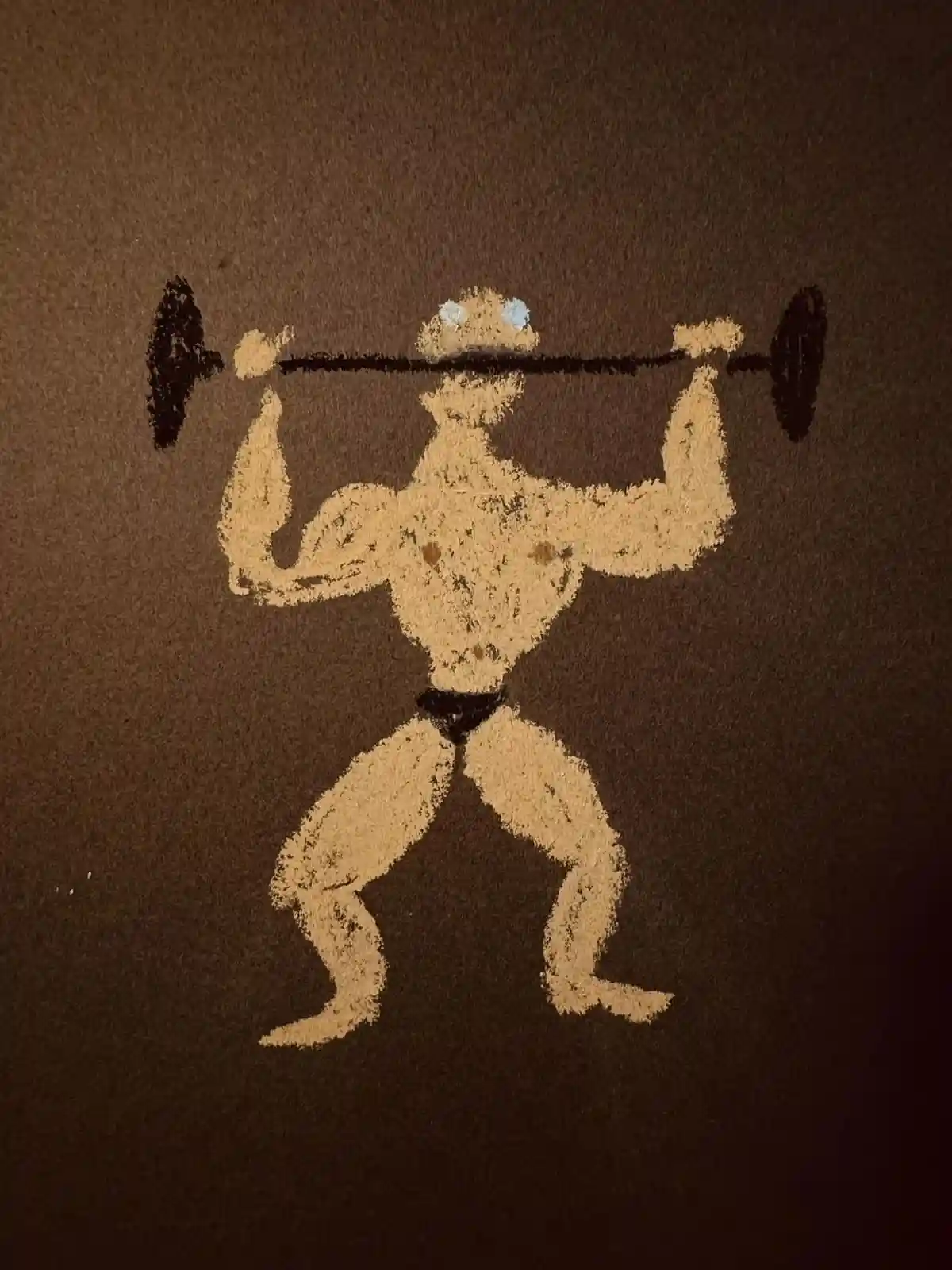 A chalk drawing on a brown surface depicts a muscular, shirtless man with a black belt, lifting a barbell across his upper…
