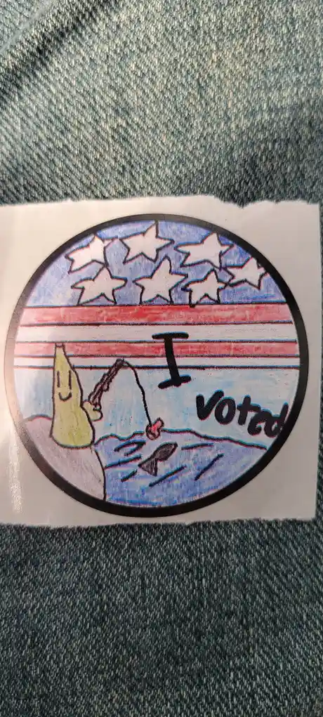 A circular sticker with an American flag design is stuck on denim fabric. The flag's stars and stripes are drawn in red…