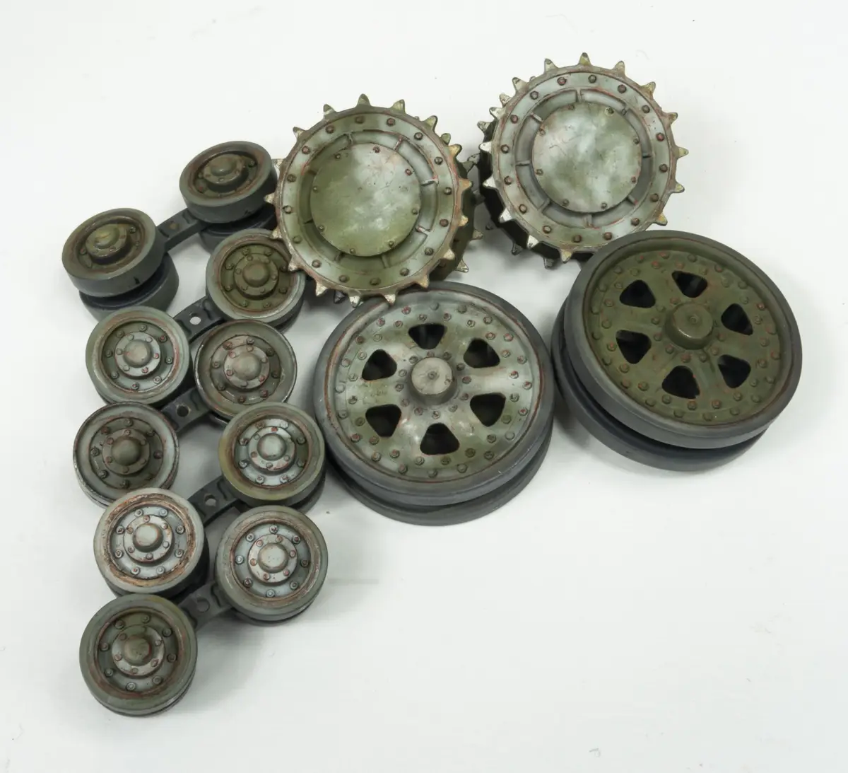 A collection of various greenish, rusty, and worn-looking metal wheels and pulleys, some with spiky rims and others with…